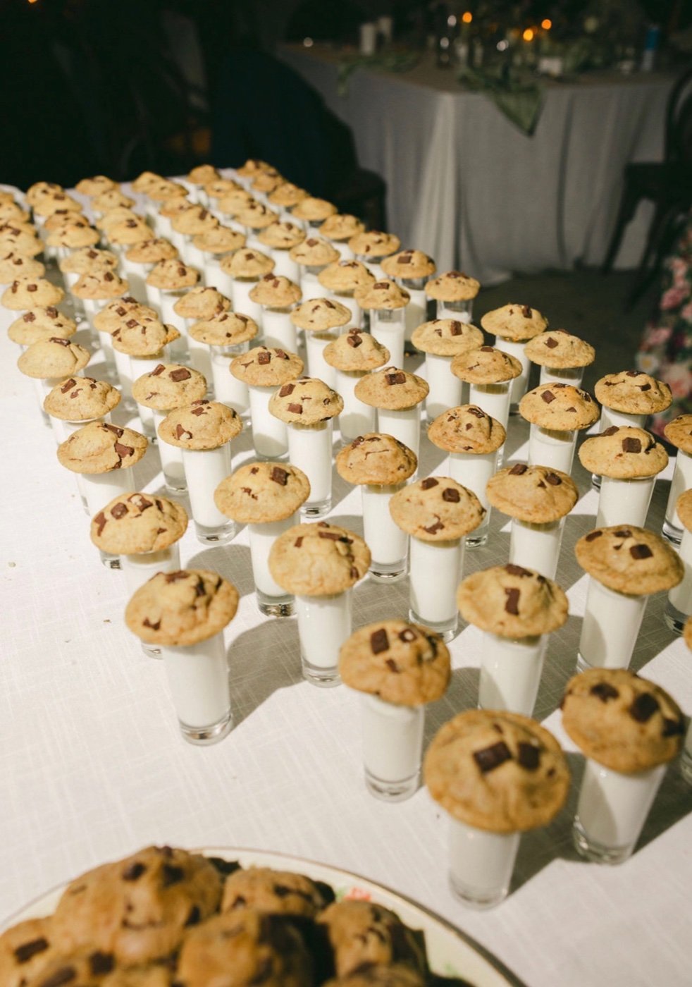 Rows of chocolate chip cookies perched on milk shot glasses at a wedding reception